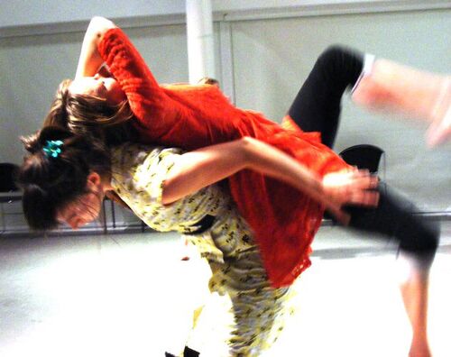 Two participants in movement with one in motion across the other's back