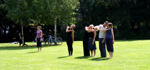 An ensemble of participants in movement in a green space outdoors