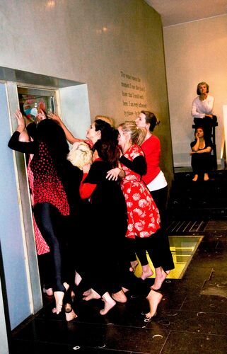 An ensemble of participants in movement in a doorway in a gallery space