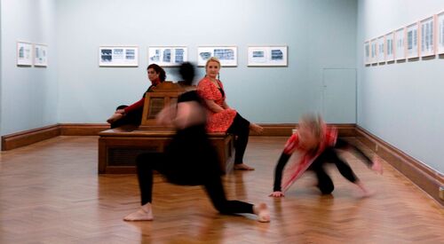 Two participants blurred in movement in a gallery space