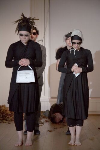 An ensemble of participants in all black costume with dark sunglasses and white accessories