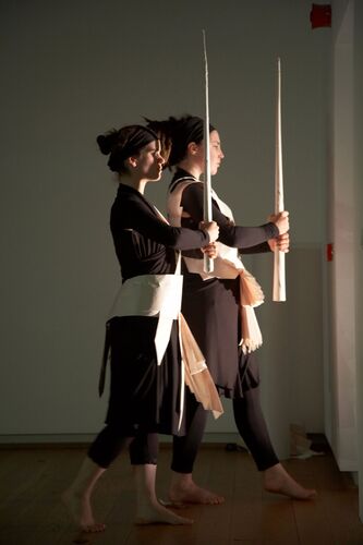 Two participants in side profile walking with long staffs