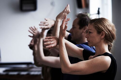 A line of figures in side profile with hands and arms in movement