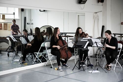 Three musicians playing instruments in a dance studio