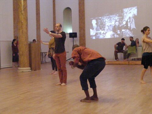 Participants in movement with projections cast on a wall behind