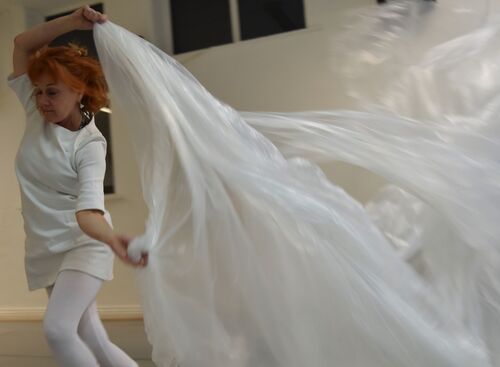 A participant in movement trailing a large plastic sheet behind