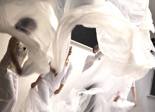 Participants in movement with large sheets of white plastic billowing