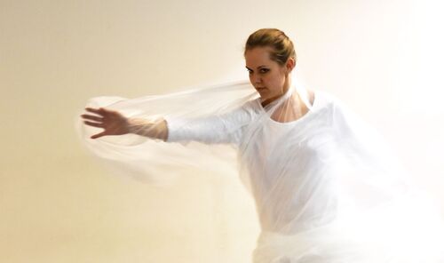 A participant in movement with a transparent plastic sheet wrapped around her