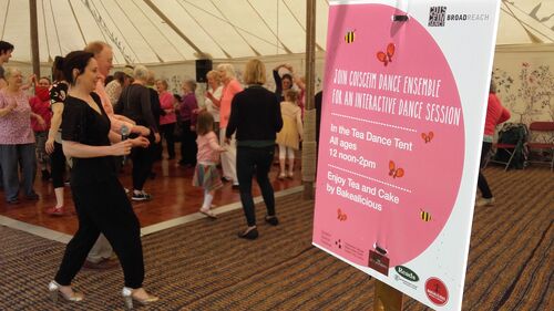 Participants dancing by a large sign for the Moveable Feast event