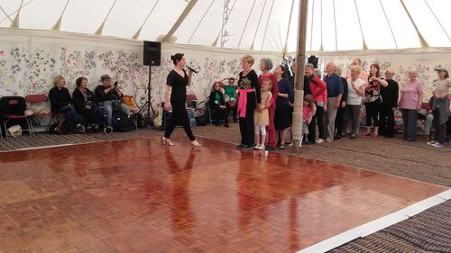 A line of participants waiting at the edge of a dancefloor in a large stretch tent