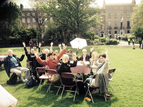 A table of participants sat outdoors with arms outstretched for the camera
