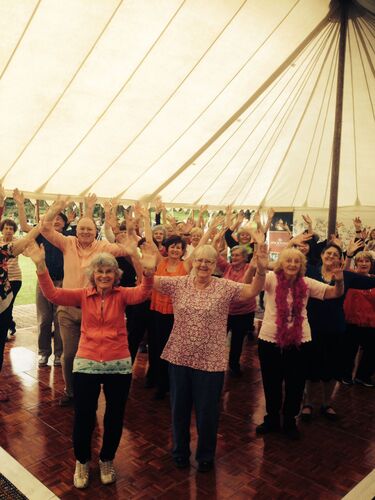 Participants with arms upraised in a large stretch tent