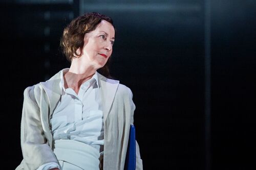 A figure seated dressed in white on stage