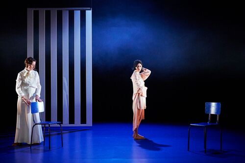 Two figures standing on a blue lit stage