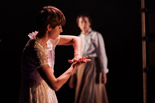 A figure in movement while a figure in the background watches