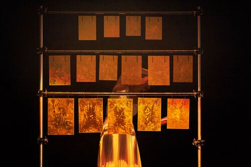 A figure in movement behind a frame of hung panels