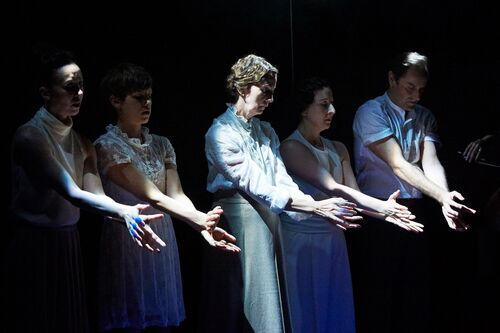 Five figures standing in a line with arms and hands outstretched into light