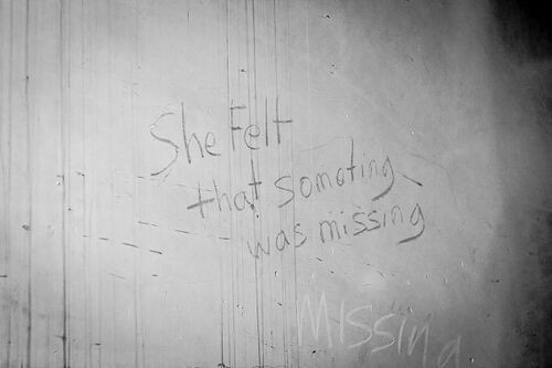 Writing on a wall reading 'She felt that something was missing'
