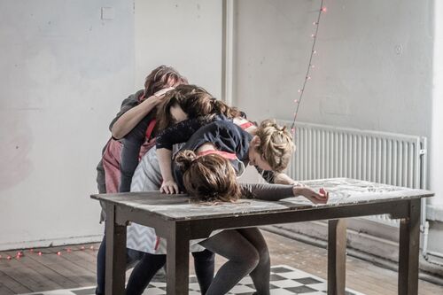 Four figures slumped over each other in single file on to the surface of a table