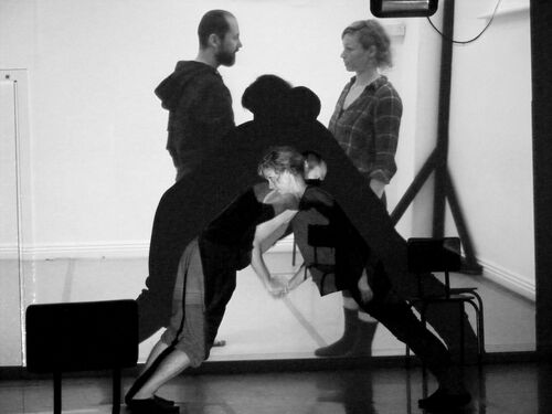 Two figures in balance leaning into each other with their projected forms behind them