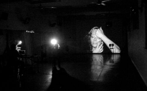 Justine Cooper's face projected on the studio wall in darkness