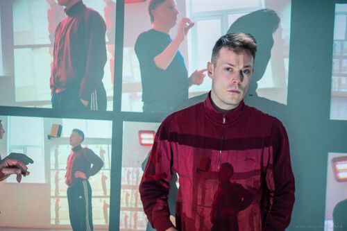 Ryan O'Neill standing against a wall with projections cast over both