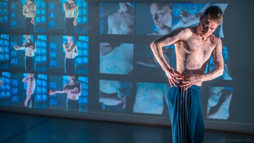 Ryan O'Neill in movement with still shots of himself in a grid projected on the wall behind