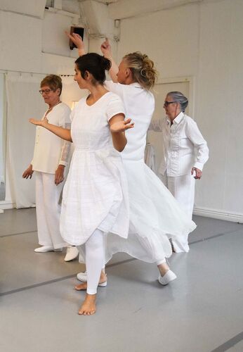 Four participants in movement together dressed all in white