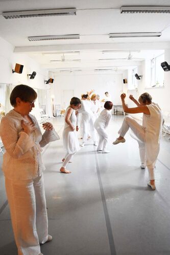 Participants in movement in a studio dressed all in white