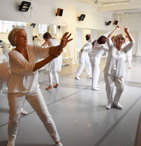 Participants in movement in a studio dress all in white