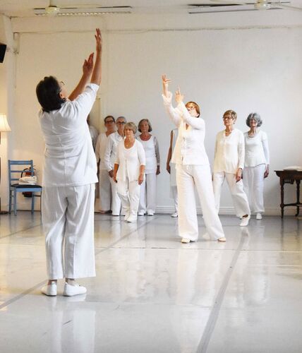 Participants in movement in a studio space dressed all in white