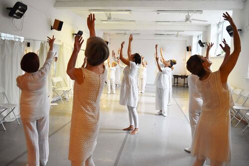Participants in movement in a studio dressed all in white