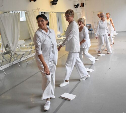 Participants dressed all in white in movement in a single file line