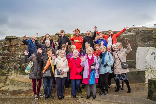 A group of older participants lined up and waving in a group photo