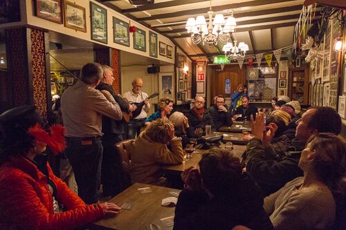 A group of musicians performing in a restaurant with audience seated at tables around them