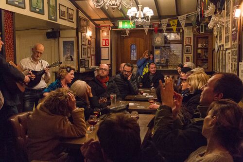 A group of musicians performing in a restaurant with audience seated at tables around them