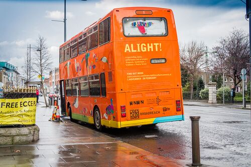 A bright orange double decker bus with ALIGHT! printed on the back