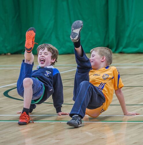 Two young boys in movement, laughing, with one leg in the air each