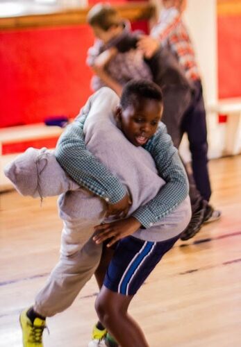 Two young children with arms wrapped around each other mid-lift