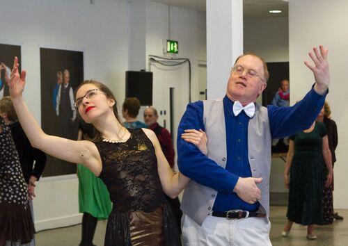 Two participants in movement with arms linked and other arms outstretched