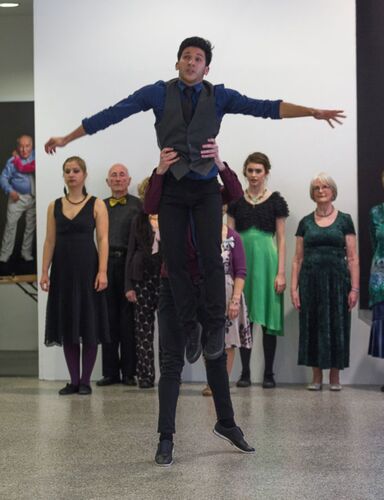 Two participants mid-lift with one being raised vertically above the others head