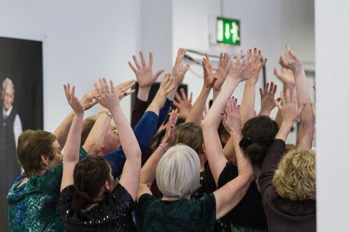 Participants in movement with their hands raised as seen from behind