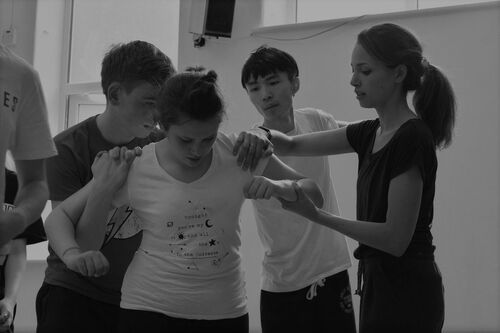 An ensemble of young people in movement in a studio
