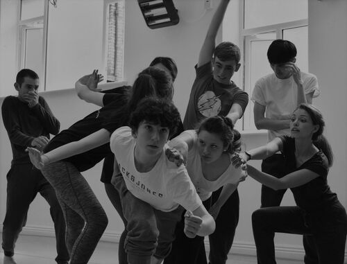 An ensemble of young people in movement in a studio