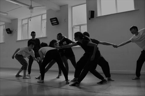 An ensemble of young people in movement in a studio