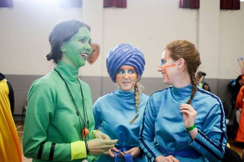 Three participants in different coloured costumes in a hall