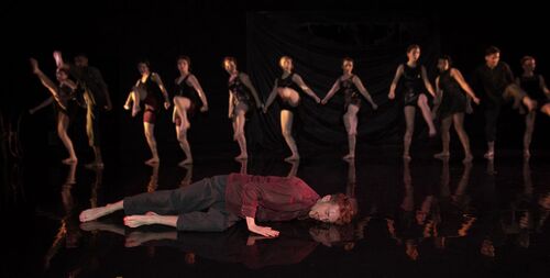An ensemble in a chorus line with one figure at the front in solo movement
