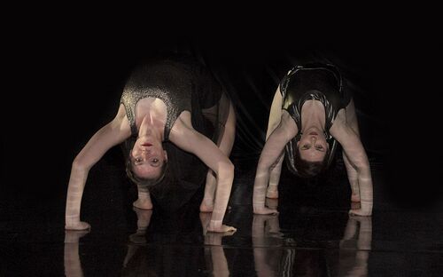Two participants in back bends on a reflective black floor