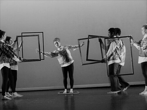 Participants in movement on stage with large empty picture frames