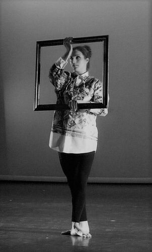 A figure in movement on stage with an empty picture frame